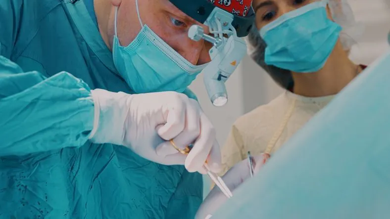 A woman is laying in a dental chair while a dentist examines her teeth.