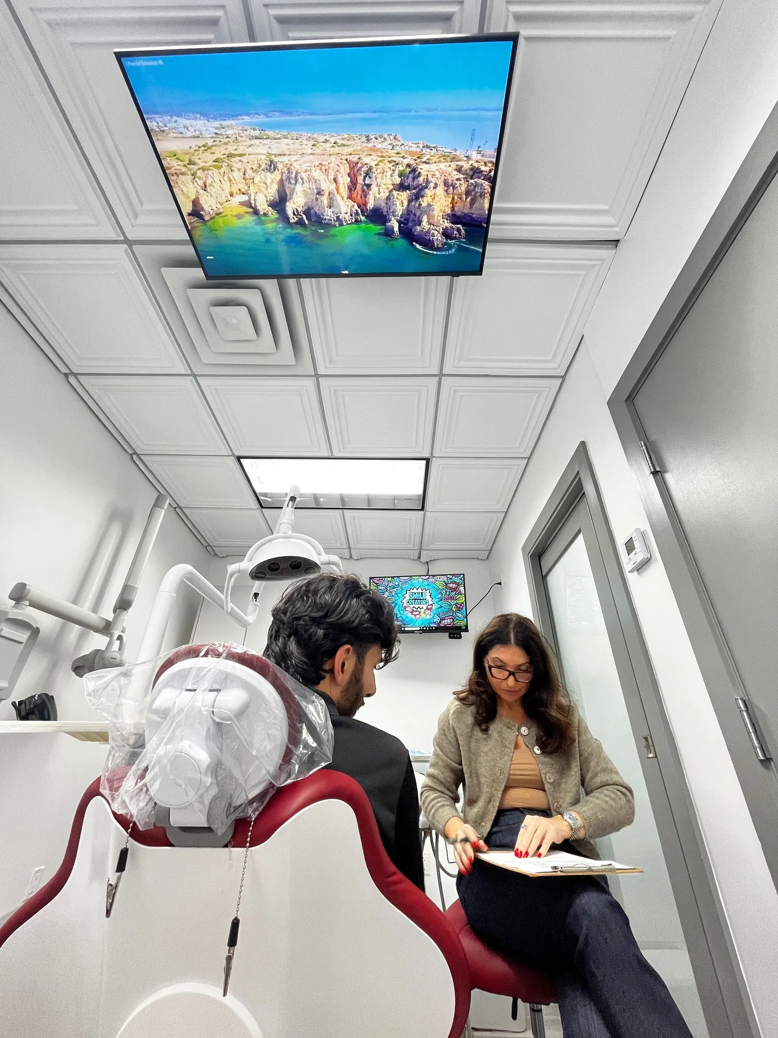Two surgeons in green scrubs operating on a patient in a dental office.