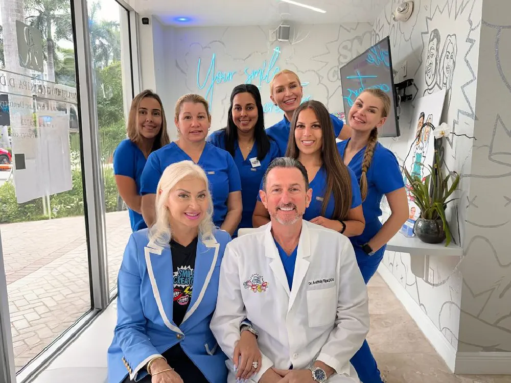 A group of doctors and nurses are posing for a picture in a dental office.