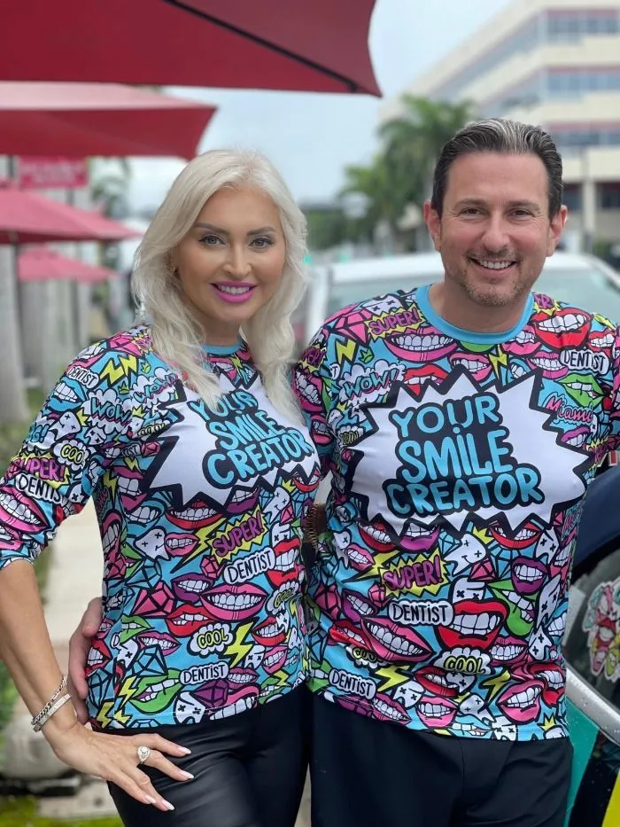 A man and a woman are standing next to each other wearing shirts that say `` your smile creator ''.