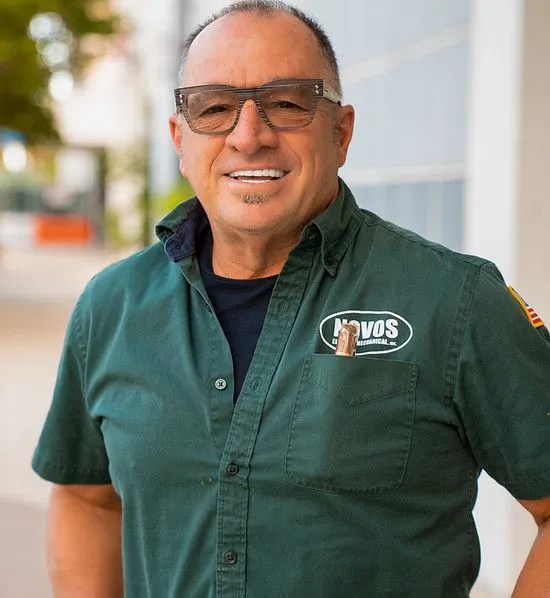 A man wearing glasses and a green shirt with the word vos on it