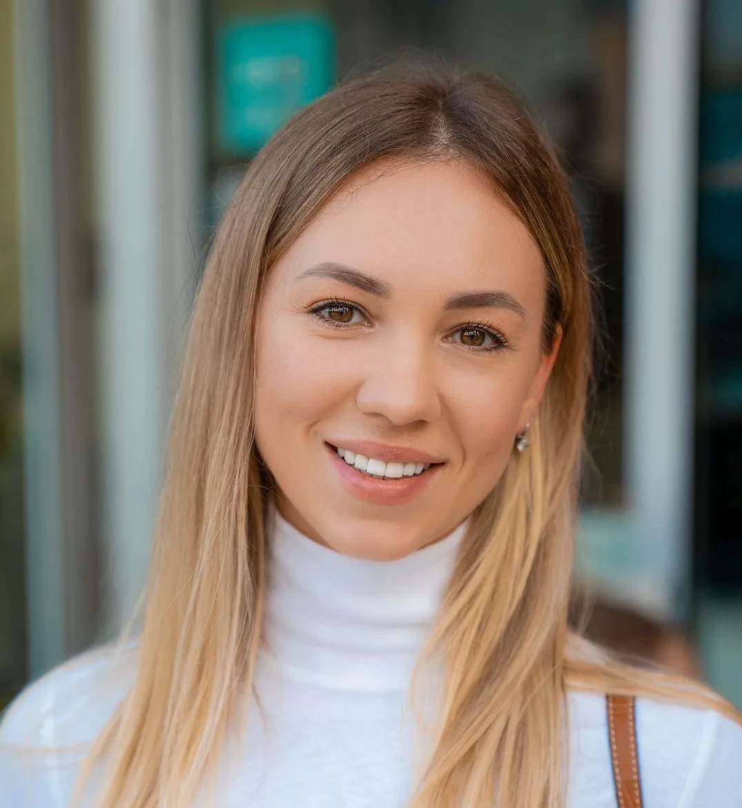 A close up of a woman wearing a white turtleneck and smiling.