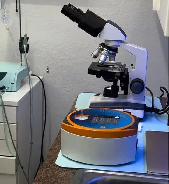 A microscope is sitting on a table next to a sink