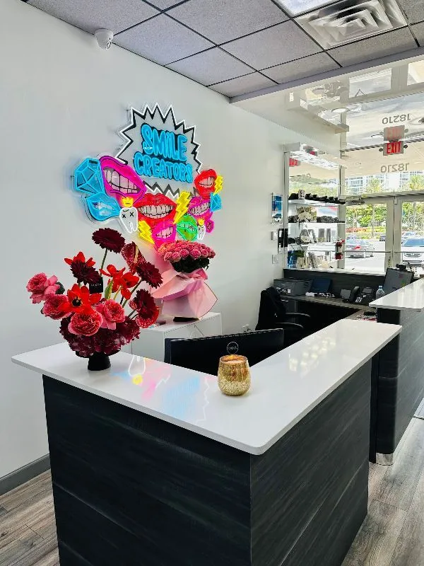 A reception desk in a salon with a vase of flowers on it.