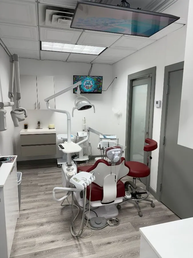 A dental office with a red chair and a tv on the wall