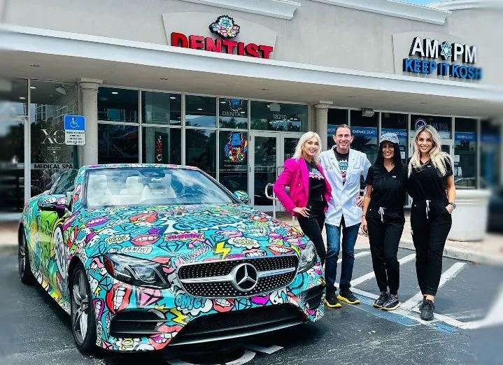 A group of people are standing in front of a colorful car.