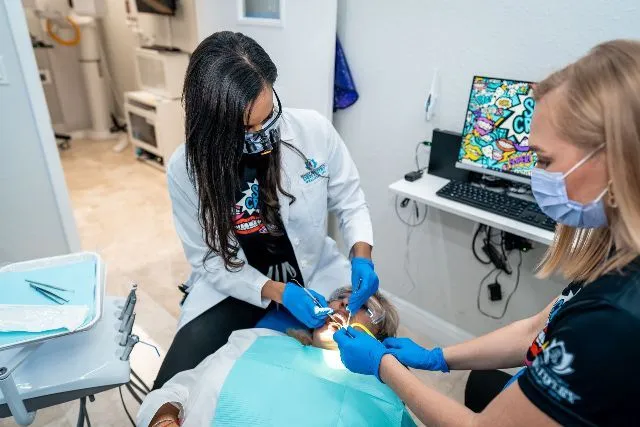 A dentist is examining a woman 's teeth in a dental office.